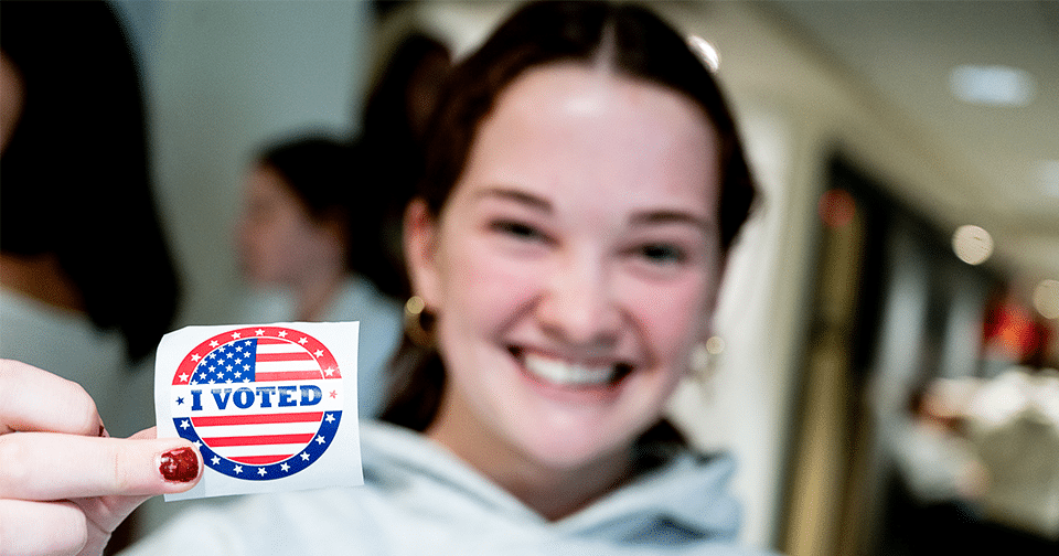 960x504_1ccday Female student holds an "I voted" sticker.