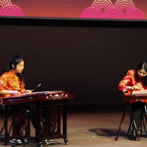 Two musicians on stage playing the guzheng and yangqin