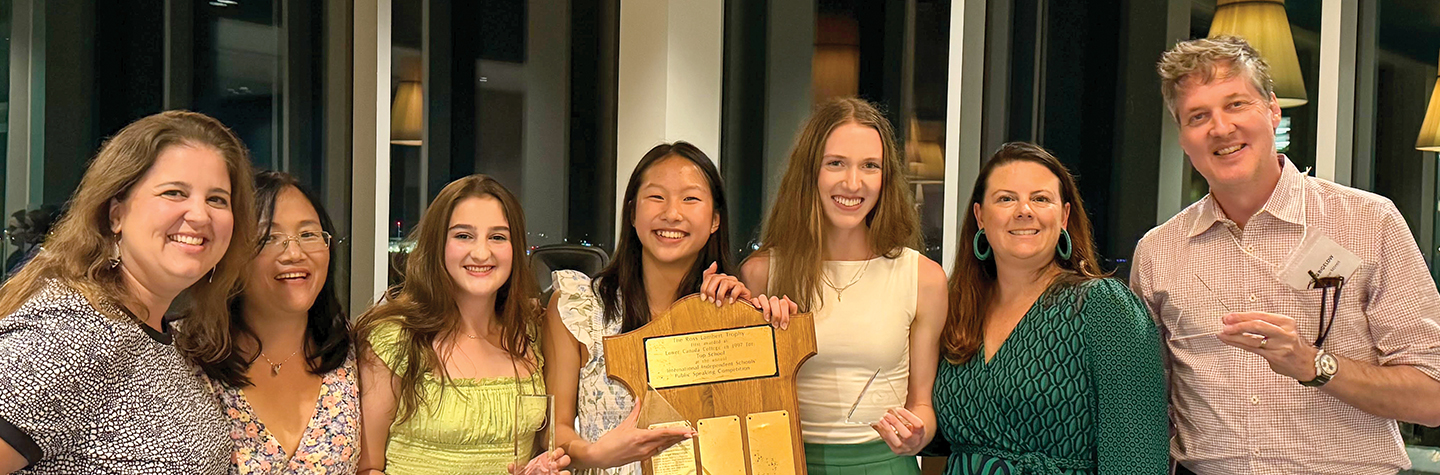 1440x475_debaters group of seven people, girls and parents holding awards