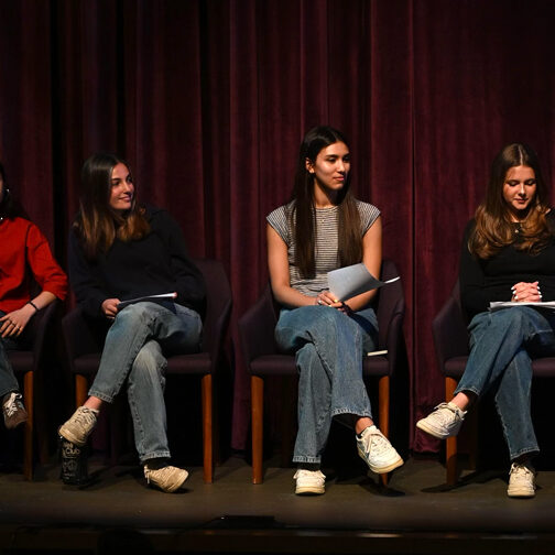 Six female-presenting students seated on stage