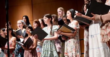 diverse group of girls in spring floral dresses singing on stage