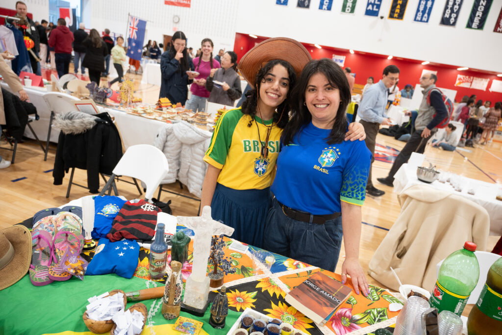 A young woman with brown hair, a hat, and a yellow and green shirt with the word "Brasil" on it next to her mother, a woman with dark hair in a blue shirt that says "Brasil"