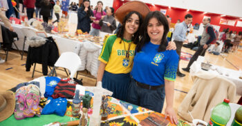 A young woman with brown hair, a hat, and a yellow and green shirt with the word "Brasil" on it next to her mother, a woman with dark hair in a blue shirt that says "Brasil"