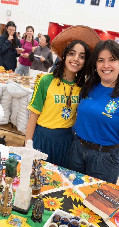 A young woman with brown hair, a hat, and a yellow and green shirt with the word "Brasil" on it next to her mother, a woman with dark hair in a blue shirt that says "Brasil"