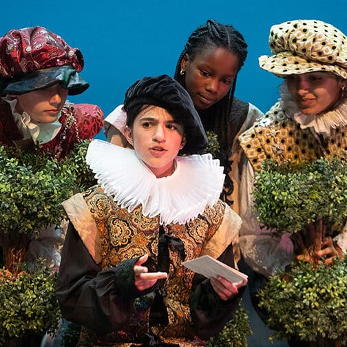 Four students on stage dressed in Renaissance costumes.