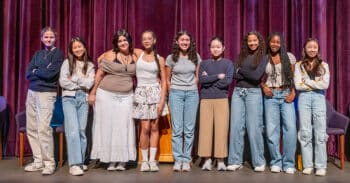 9 students stand shoulder to shoulder on stage