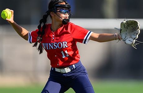 female softball catcher in red jersey throwing the ball
