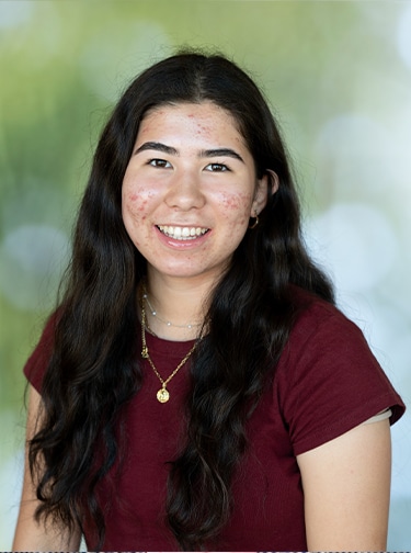 young woman with long, dark hair and a dark red, short-sleeved top