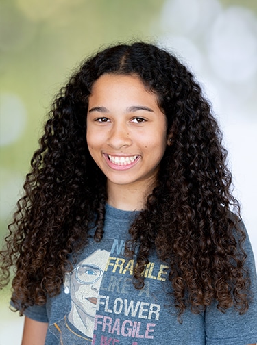 Young woman with long, dark brown, curly hair in a blue t-shirt