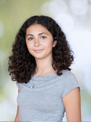 Young woman with dark, curly hair and a gray t-shirt