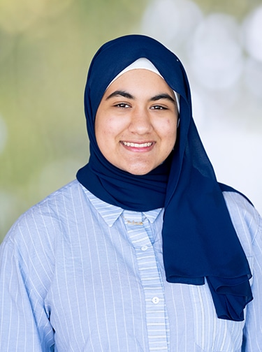 Young smiling woman wearing a hijab and light blue button-down shirt
