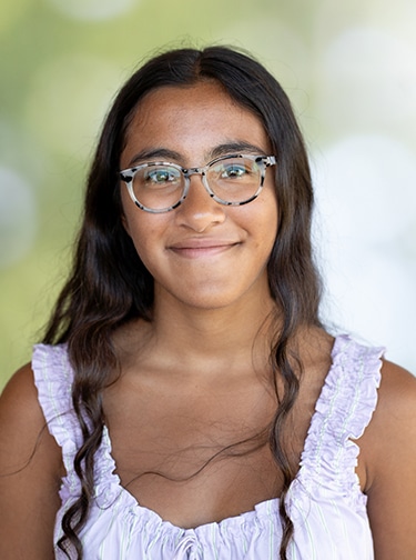 Young woman with dark brown hair, glasses, and a light purple tank top