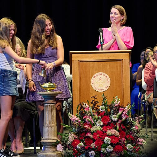 Students ring a bell on stage.