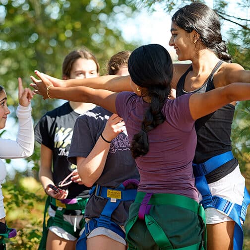 Give students wear harnesses for a ropes course activity outside
