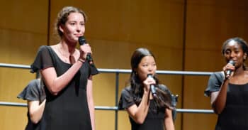 Three students sing and hold microphones