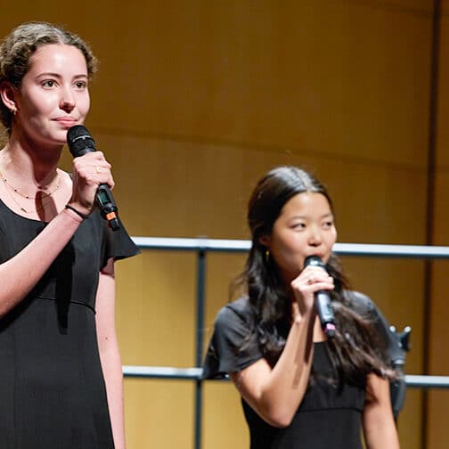 Three students sing and hold microphones