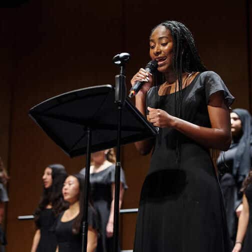 a young woman soloist leads a chorus on stage