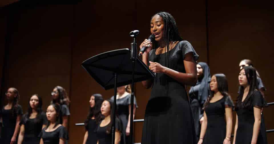 a young woman soloist leads a chorus on stage