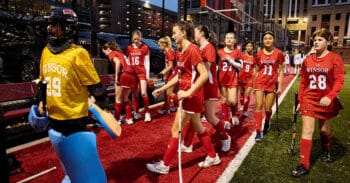 a group of field hockey players on the sideline at night