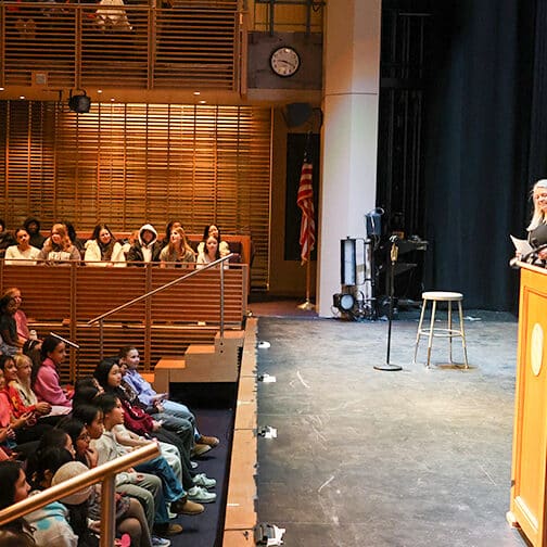 student speakers onstage addressing an auditorium audience