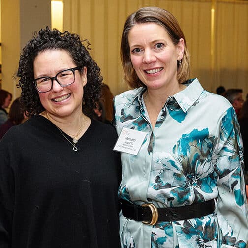 Two women posing side by side, smiling.