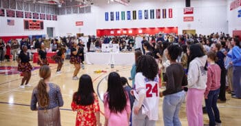 Kids in a school gym watching a dance troupe