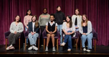 Nine seventh-and eighth-grad students sitting on a stage