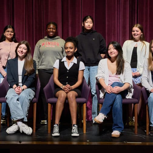 Nine seventh-and eighth-grad students sitting on a stage