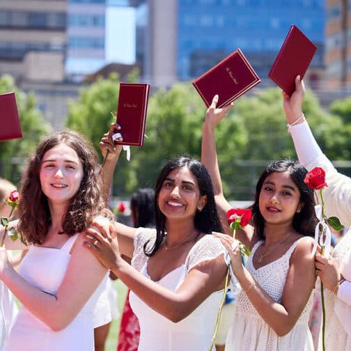 Five students hold their diplomas aloft