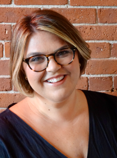 Smiling woman with short hair wearing glasses and a black top