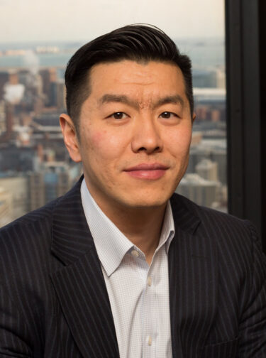 Man with short dark hair, wearing a button-down shirt and suit jacket