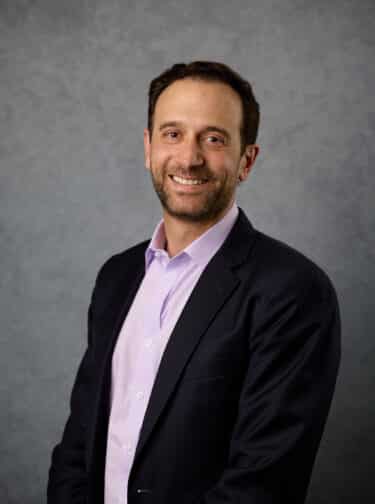 Man in a button-down shirt and dark blazer