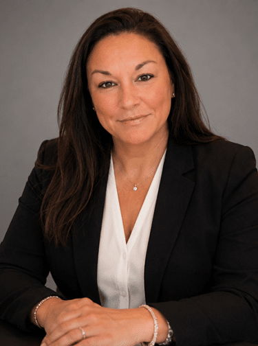 Woman with long dark hair wearing a white top and dark blazer