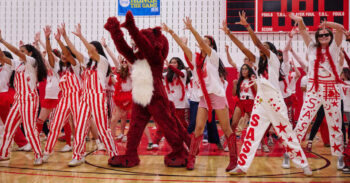 A group of students stretch their arms in the air mid dance routine.