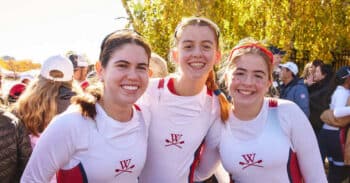 Students wear rowing uni and stand on the dock.