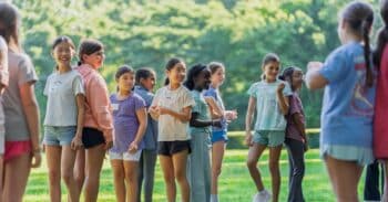 Students stand back-to-back in a field