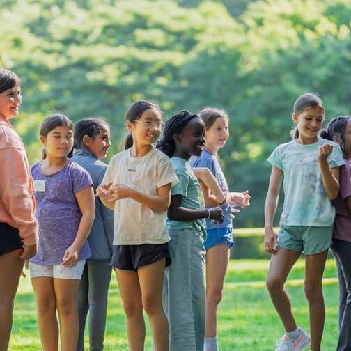 Students stand back-to-back in a field